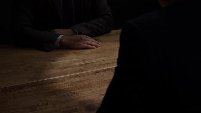 Anonymous business partners making handshake after secret meeting for hidden agenda in dark room