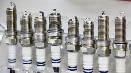New car motor iridium spark plugs in line close up on white background, car engine ignition parts