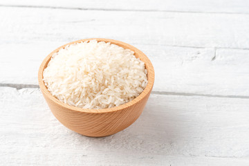 Fototapeta na wymiar White rice grains in bowl on vintage wooden background