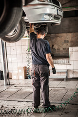 Car mechanic working in a repair garage with hydraulic car lift