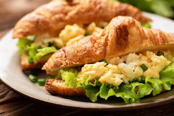 Croissant sandwich with egg cheese and green lettuce salad leaf. Tasty healthy breakfast