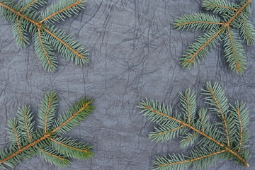 Merry christmas and a happy new year! A sprig of the green symbol of the winter holidays - spruce with decorations on a background of gray artificial leather backing.