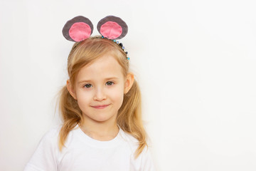  child girl on a white background, in a white T-shirt with mouse ears on her head, smiling, portrait, place for an inscription