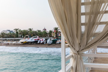 beige curtain on the background of the beach of the Mediterranean Sea at sunset