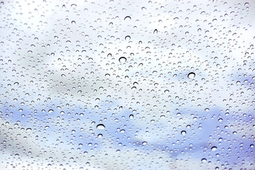 Raindrops on glass under the blue sky background.