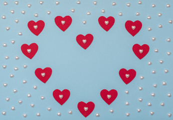 Valentine's Day blue background with red and pearl hearts. Valentine greeting card. Flat lay style. 