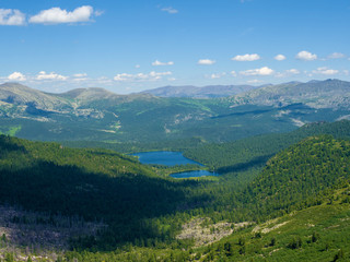 View from the pass to the green valley among the mountains. Sunny summer day in the mountains of the Western Sayan