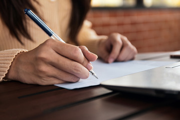 Businesswoman holding pen writing on paper document working,Close up hand write paperwork