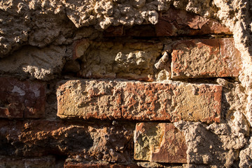 Texture of broken wall, red bricks and fallen plaster. close up
