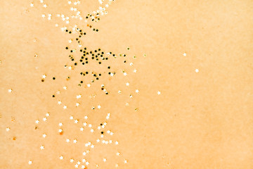 Golden star shaped glitters on yellow.