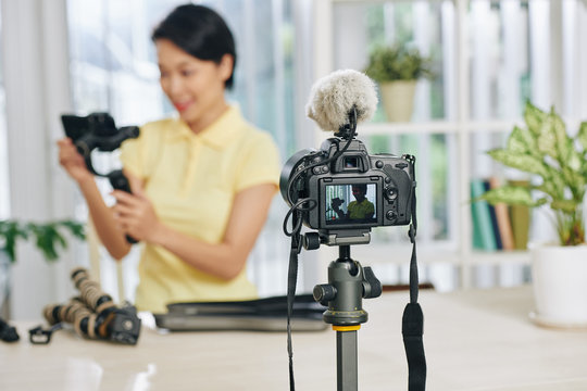 Digital camera shooting video of female blogger reviewing video production equipment