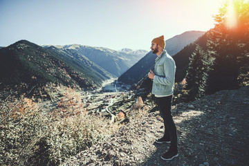 Stylish trendy hipster man traveler in a yellow hat and denim jacket stands on a background of the mountains and uzungol lake in Trabzon during Turkey travel