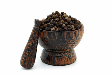 closeup the black pepper in Wooden mortar on white background , selective focus. Herbal Medicines.