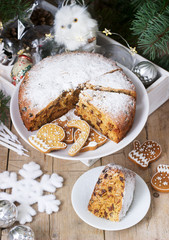 Traditional Christmas fruitcake on the background of a box with Christmas toys and fir branches.
