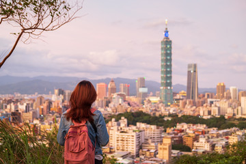 Fototapeta premium Young woman traveler looking beautiful cityscape at sunset in Taipei, Travel lifestyle concept