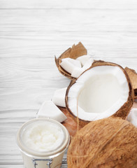 Coconut oil in airtight glass jar and shell pieces on white wooden table closeup