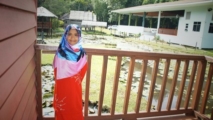 Portrait of young girl wearing traditional dress 'baju kurung' with hijab. Selected focus. Image contain certain grain or noise and soft focus when view at full resolution.