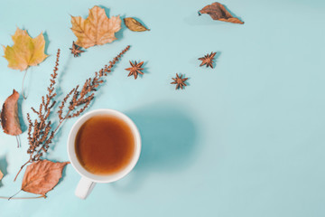 Obraz na płótnie Canvas Autumn composition. Cup of coffee, autumn leaves , cinnamon sticks and anise stars on Bright Blue pastel background. Flat lay, top view copy space.