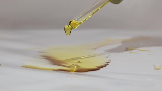 Video close up of pipette dropping black seed oil onto white background. Organic nigella sativa oil popular in the Middle and Far East.  Also referred to as black cumin oil or black caraway oil. 4K.