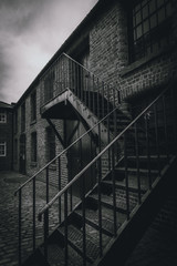 Outside metal staircase of a desolate brick building. Concept of desolation, silence and being locked.