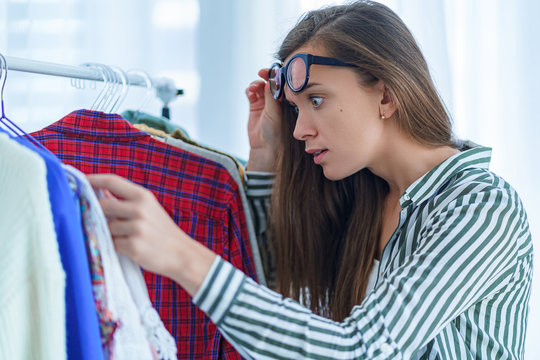 Surprised shocked woman looking at high price tag on female expensive luxury clothes during shopping clothing and choosing outfit to buy at boutique