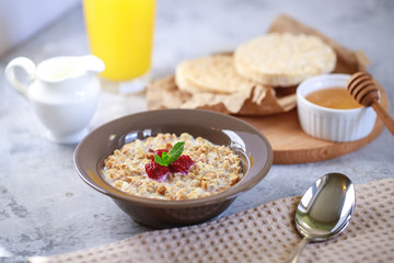 A healthy and dietary breakfast. Baked granola with milk and raspberries in a plate, whole grain breads and freshly squeezed juice. Delicious muesli.