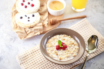 Baked granola with milk and raspberries in a plate, whole grain breads and freshly squeezed juice. A wholesome and dietary breakfast. Delicious muesli