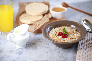 A healthy and dietary breakfast. Baked granola with milk and raspberries in a plate, whole grain breads and freshly squeezed juice. Delicious muesli.