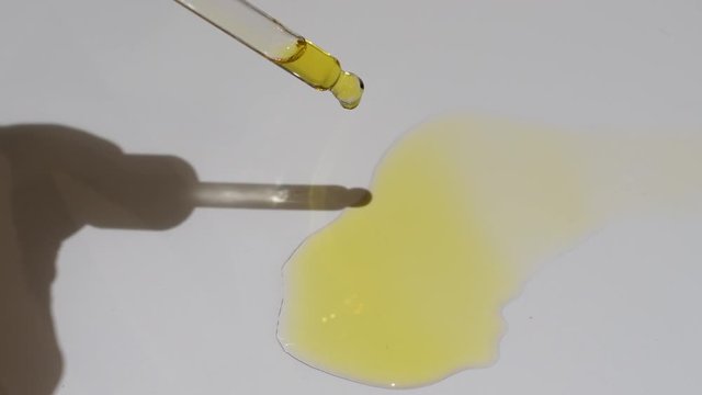 Video looking down pipette dropping black seed oil onto white background. Organic nigella sativa oil popular in the Middle and Far East.  Also referred to as black cumin oil or black caraway oil. 4K.