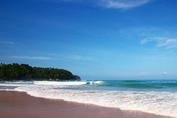 Waves, surf, and the blue sky over the sea, Karon sandy beach on a sunny day, Thailand