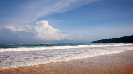 Fototapeta na wymiar Waves, surf, and the blue sky over the sea, Karon sandy beach on a sunny day, Thailand