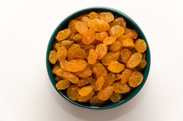 Golden raisins in a blue ceramic bowl on a white background. Healthy sweets concept. Closeup. Top view