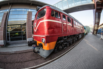 red locomotive on the platform of the railway station