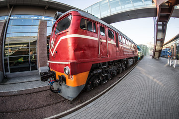 red locomotive on the platform of the railway station