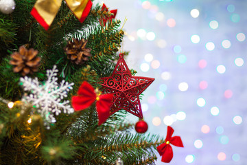 Beautiful green Christmas tree decorated with balls, big red star and garlands. Close-up photo. Sparkling background