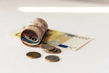 Rolled up money euro banknotes and coins on white background.