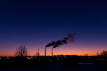 from a high pipe above the evening city a large amount of pollutants is thrown into the atmosphere from the production room