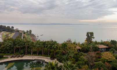 Aerial view of East Taihu or Tai Lake at sunrise in autumn, Suzhou, Jiangsu, China, with reddish sky, rocks and huts by lakeside, island on backgrounnd. Third largest fresh-water lake in China.