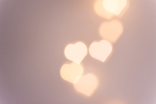 Beautiful pattern from bokeh sparkling garland lights in heart shape on pastel pinkish background. Valentine romantic love charity concept. Copy space