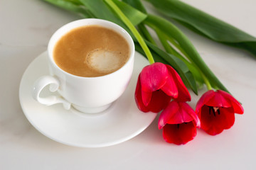 cup of coffee and tulips on a white background close-up