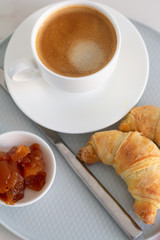 breakfast with a cup of coffee croissants and jam