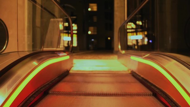 Using a escalator to the end at night highlighted by red orange lights in slowmotion