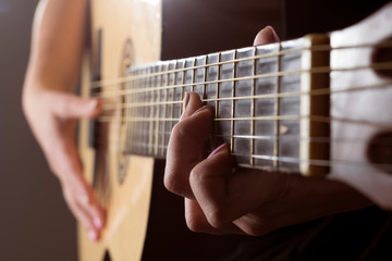 Teen girl playing an acoustic guitar. fingers in manicure on frets