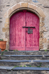 Rustic red door at the top of stone stairs