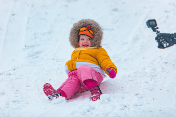 Fototapeta na wymiar little kid at sledge sliding down by winter hill
