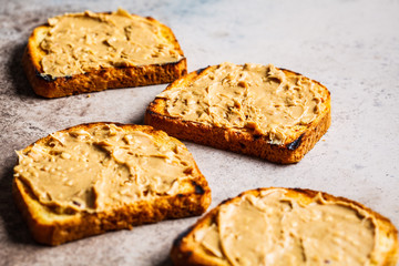 Crispy peanut butter toasts on a gray background, flat lay.