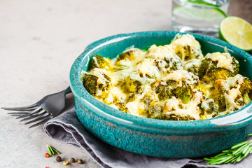 Baked broccoli casserole with cheese in blue dish, gray background. Vegetarian food concept.