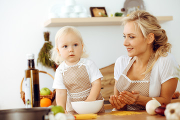 Obraz na płótnie Canvas Happy mother and little daughter cooking in kitchen. Spending time all together, family fun concept