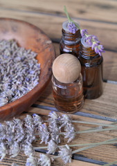 Obraz na płótnie Canvas essential oil from lavender in bottle and dried flowers in wooden bowl