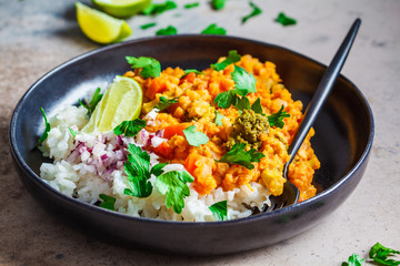 Vegetarian lentil curry with rice in black plate. Healthy vegan food concept.